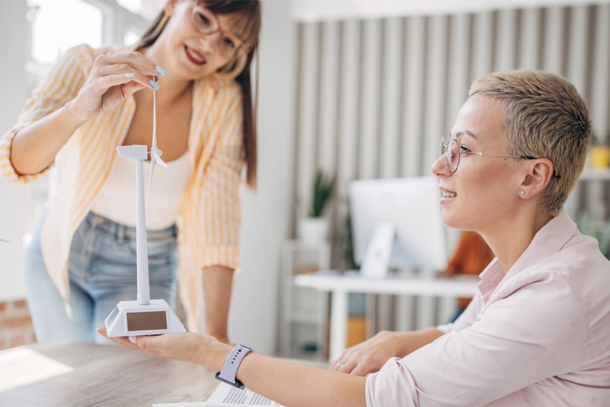 Zwei Frauen betrachten das Modell eines Windrads