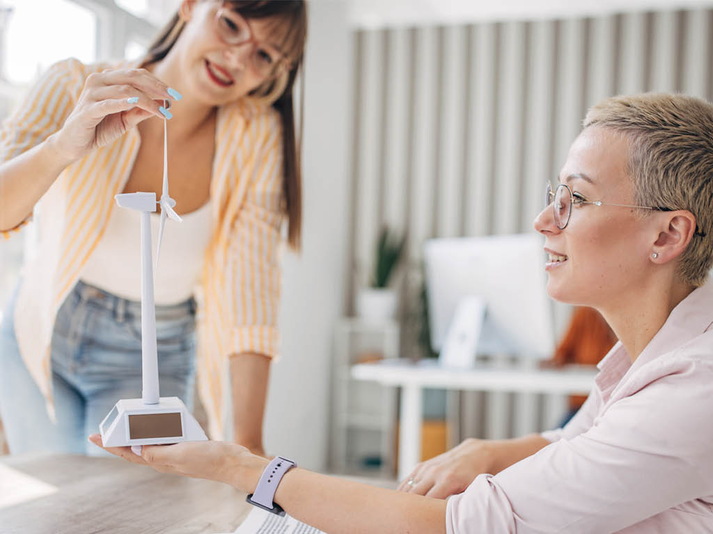 Zwei Frauen betrachten das Modell eines Windrades