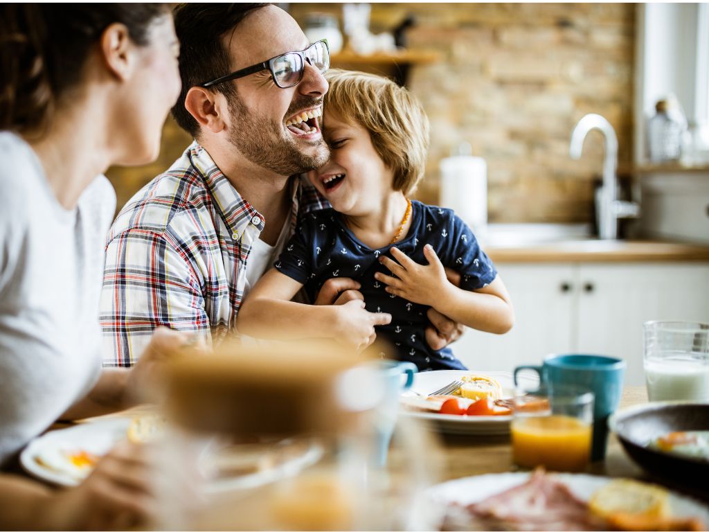 Familie am Frühstückstisch, Sohn umarmt Mutter